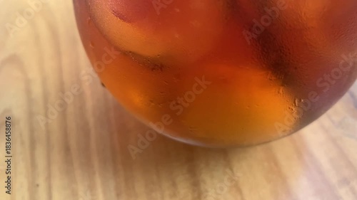 cold iced tea in a rounded glass, topped with foam and fresh mint, with a black straw. Inviting and casual, perfect for summer cafe or lifestyle imagery