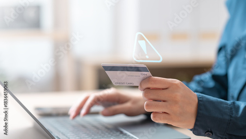 Person holding credit card with virtual warning icon, representing fraud alerts and digital security risks. Suspicious charge fraud alert. symbolizing fraud alerts and secure transaction monitoring.