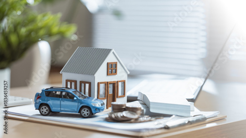 Mini house, car model, coins, and documents on a bright office desk representing finance and property planning. Monthly payment budget debt. Calendar expenses cost management. Loan car, Home finances.
