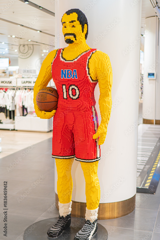 Obraz premium Life-sized Lego sculpture of a red basketball player number 10 in a neutral background, posed actively with one arm on hip and holding a basketball - Kyiv, Ukraine - November 12, 2025