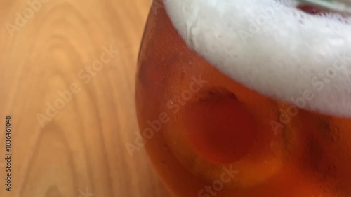 cold iced tea in a rounded glass, topped with foam and fresh mint, with a black straw. Inviting and casual, perfect for summer cafe or lifestyle imagery