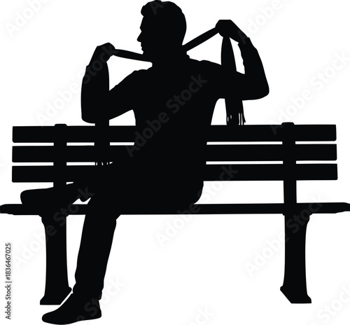 Silhouette of a man sitting a park bench taking off or adjusting his tie