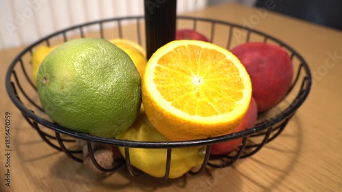Fresh fruit basket with oranges, lemons, and a green citrus fruit on a table