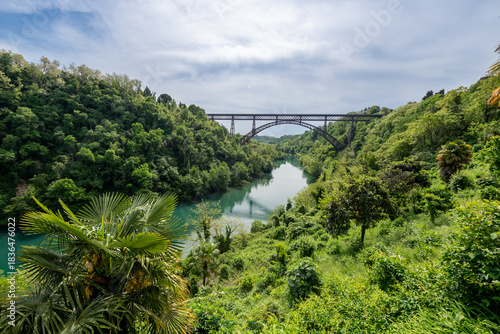Bild auf Leinwand San Michele Bridge spans the Adda River with its elegant iron arch, one of the world’s tallest single-span iron bridges, standing proudly amid lush hills and reflective waters