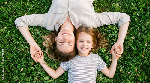 Fototapeta Naklejka Na Ścianę i Meble -  Mother and child lying grass top view copy space picnic park summer nature family relaxing mom kid looking up happy smiling green lawn outdoors vacation lifestyle leisure togetherness love concept