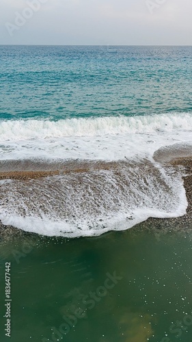 Turquoise sea, waves rolling are onto the shore with white foam. Calm coastal scene perfect for travel, relaxation, and nature-themed projects