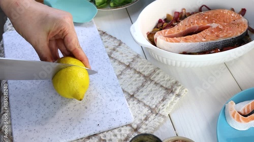 Chef preparing salmon steak with lemon and vegetables
