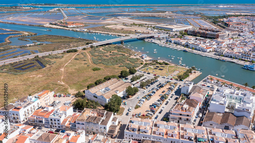 Tavira in Algarve shows the Gilao river, boats, and buildings from a high view. The area includes fields and water canals under a clear sky