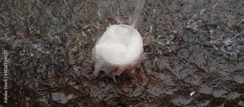 rainwater from the house gutter into the container, creating splashes and foam overflows