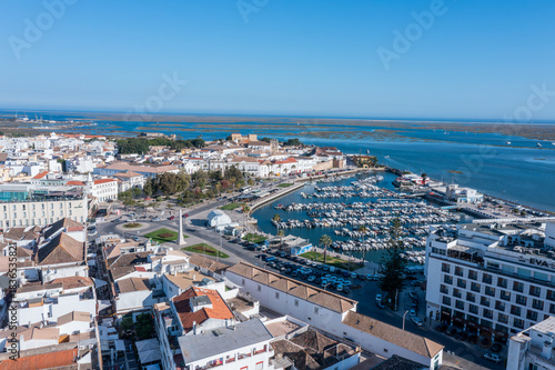 Visitors enjoy the lively dock area in Faro, Algarve, where boats are moored. The old town offers views over Ria Formosa and surrounding buildings