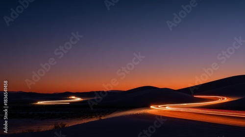 Serene Desert Landscape at Dusk Featuring Gentle Sand Dunes and Light Trails from Vehicle Movement Under a Stunning Twilight Sky