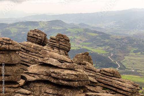 Limestone Rock Formation Overlooking Village in Antequera. Weathered limestone rocks rising above a quiet village on a rainy winter day in El Torcal, Spain.