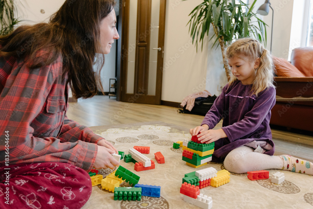 Fototapeta premium Mother and child building with colorful blocks in cozy home setting
