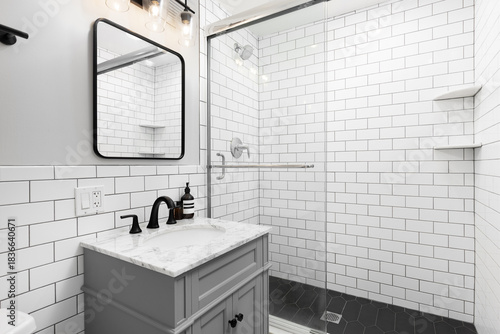 A bathroom with a grey cabinet with a white subway tile backsplash and tiled shower with a glass sliding door.
