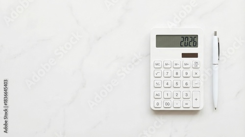 White calculator showing 2026 on clean surface with pen beside it. Minimalist financial planning tool for future budgeting and annual goals. Color of the year 2026 concept in simple design for office