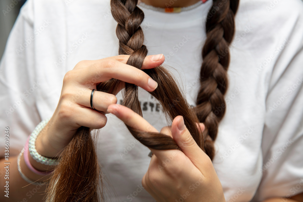 Naklejka premium młoda dziewczyna czesze włosy i plecie warkocze