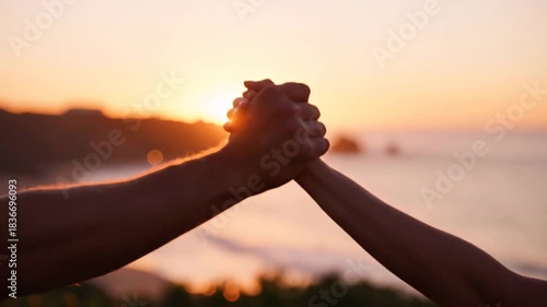 Two people shaking hands at sunset on the beach, celebrating success friendship or partnership in nature with epic ocean view, aerial shot