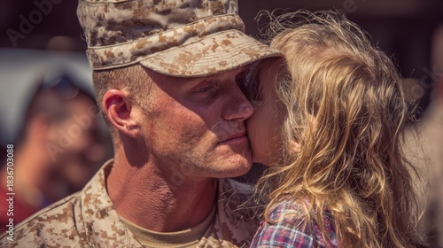 Soldier greets child at homecoming event with a warm embrace and kiss at a military base during daytime