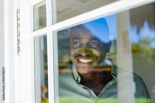 White window frame is casting blue sky and green foliage at home, glass is showing highlights
