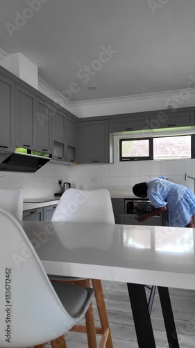 Lilongwe Malawi Africa. 01.11.2025. Video.  African woman in a short blue dress working in a modern kitchen