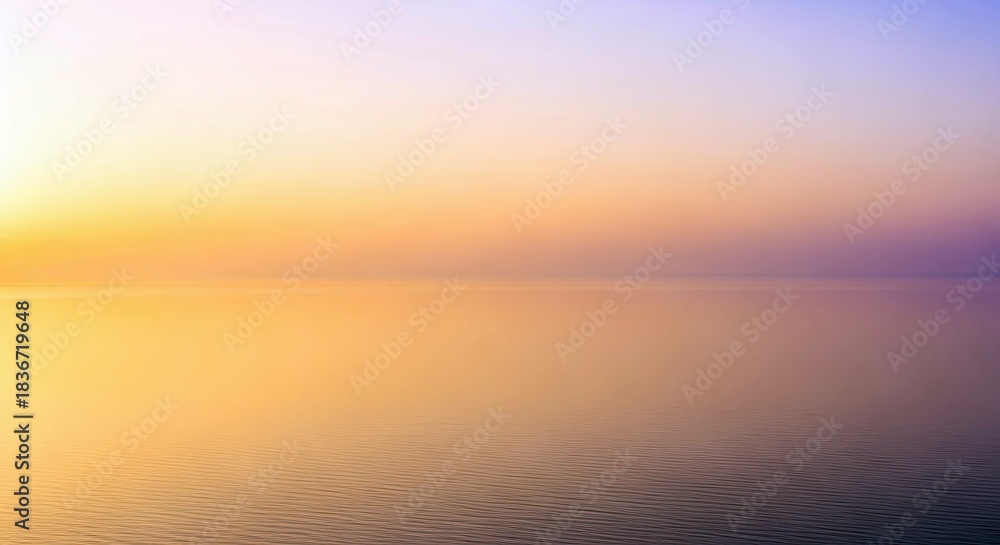 Fototapeta premium A tranquil scene of water reflecting the colors of a sunset sky. The water is smooth and the sky is a gradient of orange, yellow, and purple.