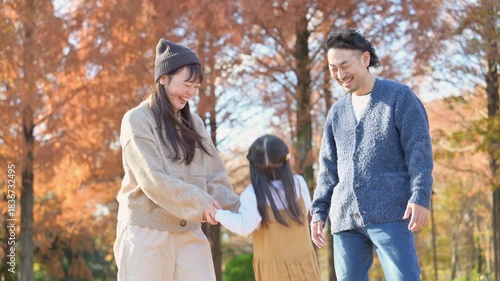 秋の公園で遊ぶ家族 お出かけやレジャーのイメージの手を繋ぐ、ジャンプなどで仲良し　ほのぼの家族の動画