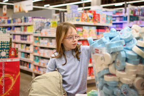 A girl chooses socks or pajamas with a Christmas print. Holiday shopping concept. Christmas gifts.