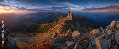 Majestic mountain ridge at sunrise, bathed in golden light, with rocky foreground