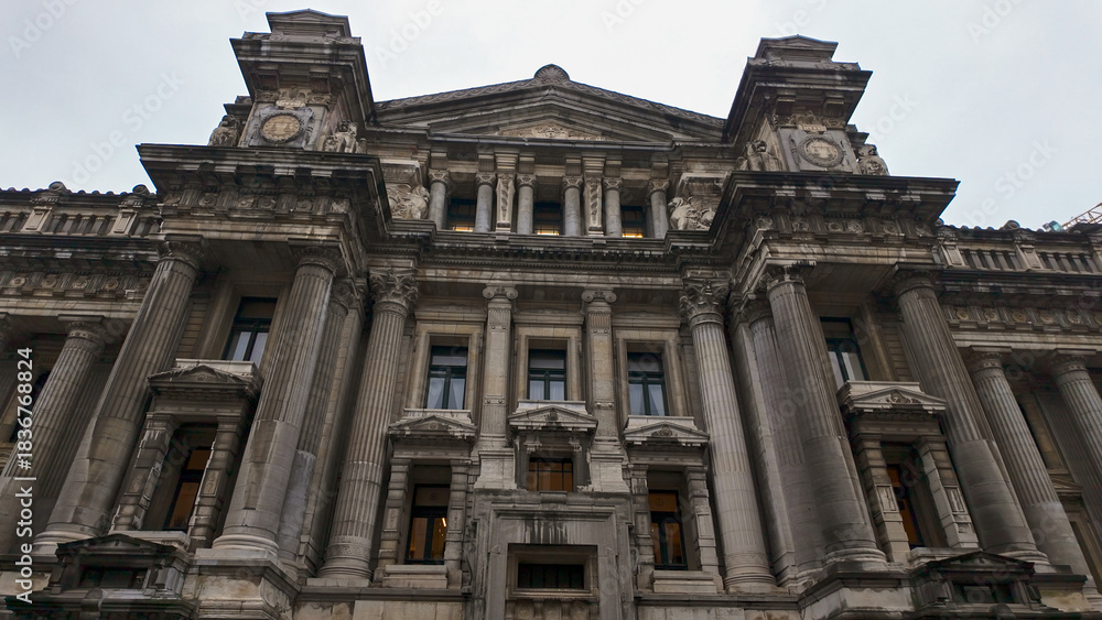 Naklejka premium BRUSSELS, BELGIUM - NOVEMBER 26, 2025 - Ornate facade of the Palace of Justice in Brussels, Belgium, under a cloudy sky