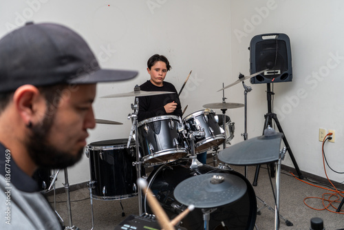 Young drum student watching the instructor closely as they play together at the drum kit. Private drum lesson focused on rhythm, percussion skills, and musical learning