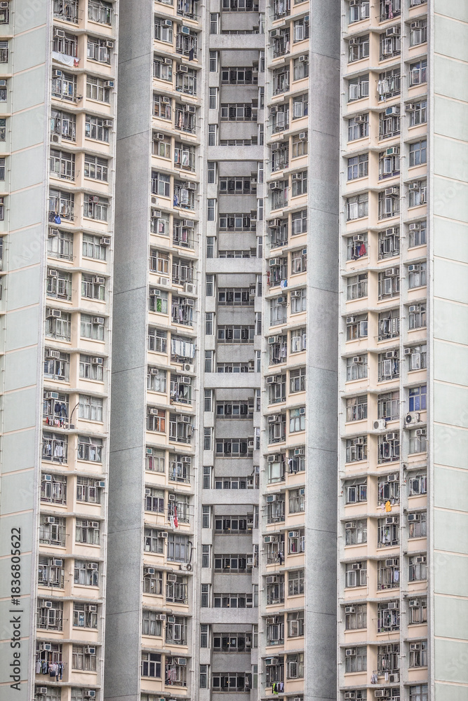 Fototapeta premium A high-rise residential building with repetitive balconies, laundry, and air conditioning units, emphasizing vertical urban density.
