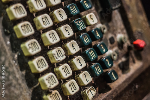 A vintage mechanical cash register with color-coded buttons arranged in numeric grid, showing signs of wear.