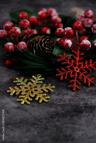 Season's greetings scene. Top view of Christmas decorations, balls, rustic star, holly berries, frosty spruce branches, confetti on green backdrop, perfect for messages or promo. text space concept