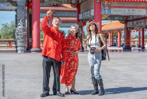 asian senior couple in cheongsam traditional clothes talking with young caucasian female traveller at chinese temple