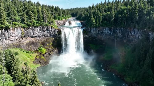 Majestic Triple Waterfall Cascading Down Rugged Cliffs Surrounded by Lush Green Forest Under a Clear Blue Sky