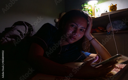 Thai Girl wearing pajamas uses phone on bed