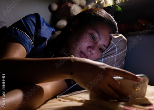 Thai Girl wearing pajamas uses phone on bed