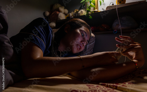 Thai Girl wearing pajamas uses phone on bed