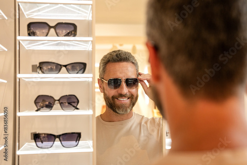 Trendy sunglasses accessories for men. Eyewear collection. Fashion look with sunglasses. Man choosing sunglasses in shop. Sunglasses model in fashion store. Fashionable man prefer this one