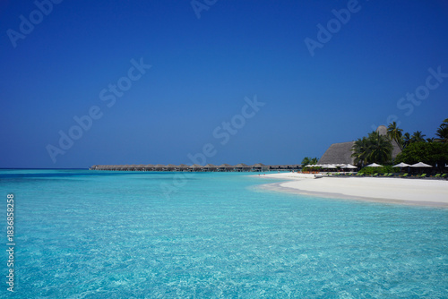 Fototapeta Naklejka Na Ścianę i Meble -  Overwater Bungalows and White Sand Beach in the Shallow Turquoise Sea of Maldives