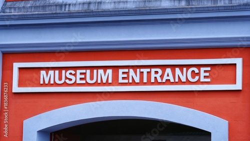 Closeup of exterior facade with Museum Entrance sign in white text against orange wall in Wellington, New Zealand Aotearoa