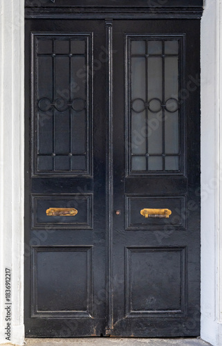 Classic wooden double door with decorative panels and vintage handles, framed by marble walls, showcasing traditional architecture and elegant historic craftsmanship.