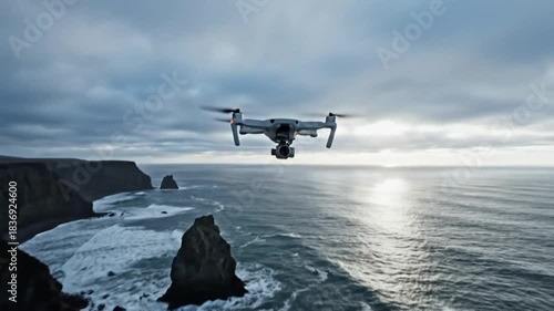 Aerial drone capturing dramatic coastal cliffs and ocean waves under a cloudy sky