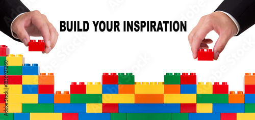 Hands building wall with colorful toys, displaying inspiration concept
