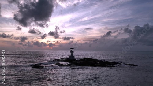 Aerial view of tranquil seaside lighthouse at sunset shoreline 