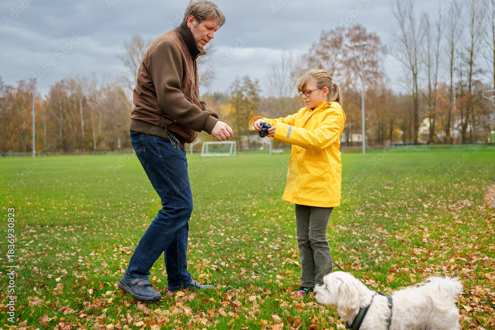 Fototapeta premium Little girl and father going for a walk with Maltese dog puppy. Happy child and pet.