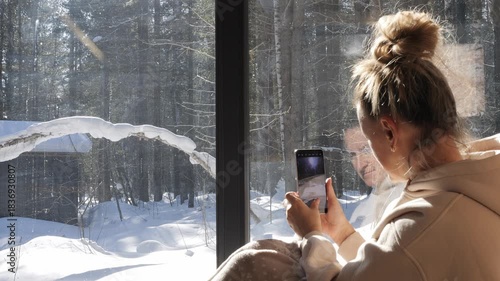 Mindful living shows balance of technology and silence near window Woman with phone captures calm view where forest gives harmony forest adds depth and forest becomes symbol of peaceful lifestyle