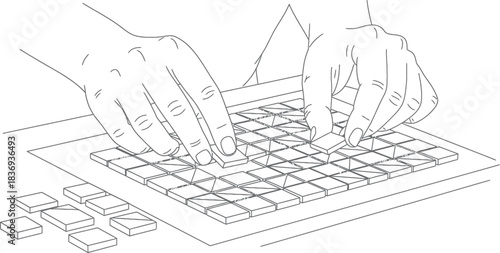 Hands placing tiles on a grid pattern