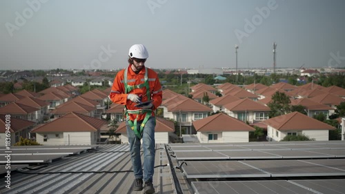Blue collar worker is inspecting solar panel at rooftop of factory. Energy, sustainability.