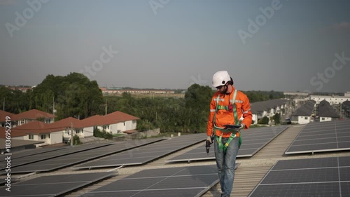 Blue collar worker is inspecting solar panel at rooftop of factory. Energy, sustainability.